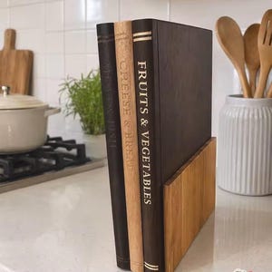 May include: Three rectangular wooden cutting boards standing upright in a light wood holder. The boards are labeled with gold text reading FRUITS & VEGETABLES, CHEESE & BREAD, and MEAT & FISH, featuring dark and light wood finishes for organization.