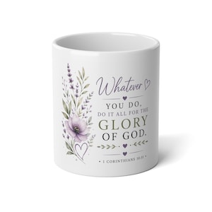 May include: A white ceramic mug featuring a floral illustration of purple lavender and a flower on the left side. The text reads: Whatever YOU DO, DO IT ALL FOR THE GLORY OF GOD. 1 CORINTHIANS 10:31. Small purple hearts and decorative lines accent the text.