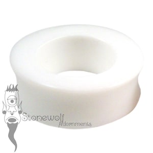 Può includere: Un dilatatore per orecchie circolare bianco solido con una finitura liscia e opaca e un centro concavo. L'oggetto presenta un design con bordo svasato ed è posizionato accanto a un logo grafico in bianco e nero che recita Stonewolf Adornments.