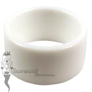 May include: A solid white ring with a smooth, matte finish and a wide, cylindrical band. The surface is plain and unadorned, featuring a consistent opaque white color throughout. The logo Stonewolf Adornments is visible in the lower left corner.