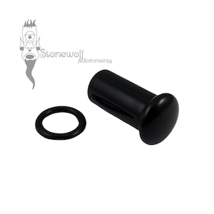 May include: A black ear plug with a smooth, cylindrical body and a rounded front flare, accompanied by a separate black rubber O-ring. The logo for Stonewolf Adornments is visible in the upper left corner, featuring a stylized cyclops face.