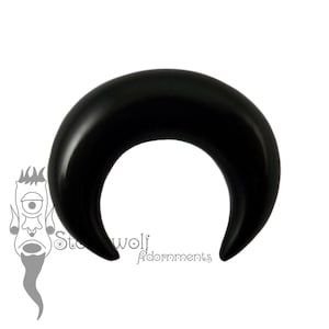 May include: Black crescent moon shaped ear gauge made of wood.