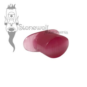 May include: A magenta-colored ear plug with a smooth, polished surface and a cat's eye effect. The object features a flared design with a rounded, slightly asymmetrical face. The text Stonewolf Adornments is visible in the upper left corner.