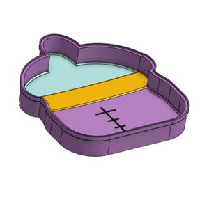 May include: A purple cookie cutter shaped like a baby bottle with a light blue top section, a yellow middle band, and a purple bottom section featuring a black vertical line with three horizontal cross marks centred on the lower portion.