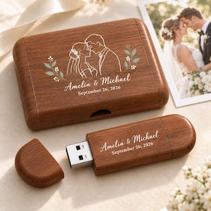 Puede incluir: Una caja rectangular de madera para memoria USB y una memoria USB a juego, ambas grabadas con los nombres Amelia & Michael, la fecha 26 de septiembre de 2026 y una ilustración lineal de una pareja rodeada de ramas verdes.