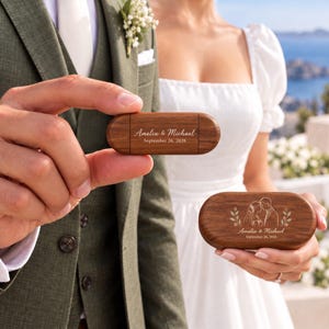 Può includere: Due chiavette USB in legno di forma ovale con venature color marrone scuro. Una è incisa con il testo Amelia & Michael September 26, 2026. L'altra presenta un'illustrazione a linee di una coppia con lo stesso testo.