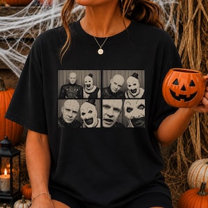 May include: A black short-sleeve t-shirt featuring a graphic print of four black and white photo booth panels. The images depict Pinhead from Hellraiser and Art the Clown from Terrifier side by side in various poses with distinct facial expressions.