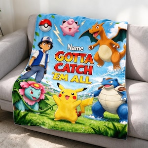 Könnte beinhalten: Eine blaue Fleecedecke mit einem farbenfrohen Grafikdruck von Ash Ketchum, Pikachu, Glurak, Bisaflor, Turtok, Pummeluff und einem Pokéball. Der Text lautet Name, GOTTA CATCH 'EM ALL in fetten gelben und roten Buchstaben vor einem blauen Himmel.
