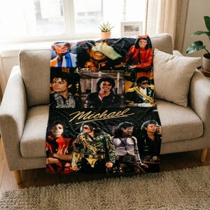 May include: A rectangular fleece throw blanket featuring a collage of various photographs of Michael Jackson in different outfits and poses. The name Michael is printed in a gold cursive script across the center of the black background.