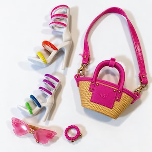 May include: A set of doll accessories including two white high-heeled sandals with multi-colored straps, a straw-textured handbag with pink trim and the letters MF, a pair of pink butterfly-shaped sunglasses, and a small pink beaded ring.