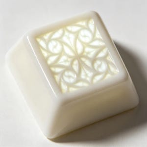 May include: A square, off-white mechanical keyboard keycap featuring a raised, intricate, repeating lattice pattern on its top surface. The keycap has a smooth, glossy finish with a slightly translucent quality, showcasing a detailed geometric design.