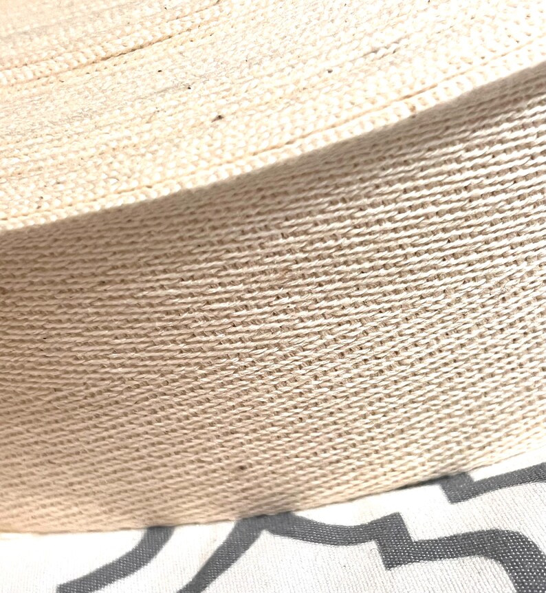 May include: Close-up of a natural beige cotton webbing, showing the woven texture of the fabric.