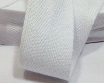 May include: White cotton twill tape with a herringbone pattern. The tape is folded and rolled up.