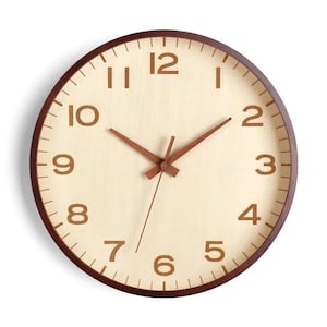 May include: A round wall clock with a dark brown wooden frame and a light beige wooden face. The clock features dark brown Arabic numerals from one to twelve and matching dark brown hour, minute, and second hands centred on the dial.
