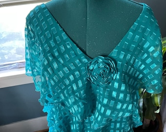 May include: Teal blue layered dress with a square pattern and a large teal blue flower embellishment on the bodice.
