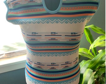 Könnte beinhalten: Ein weißer ärmelloser Pullover mit einem geometrischen Muster in Blautönen, Orange und Grün. Der Pullover hat einen runden Ausschnitt.