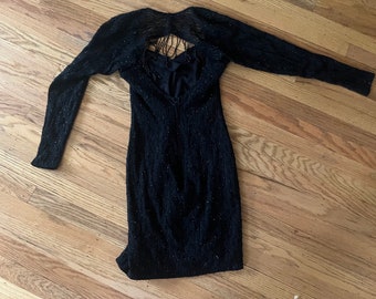 May include: A black sequined dress with long sleeves and a keyhole back with fringe detail.