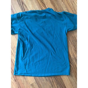 May include: A teal blue t-shirt with short sleeves. The shirt is made of a soft, comfortable fabric.