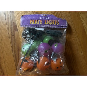 May include: A package of electric Halloween party lights with green, purple, and orange bulbs shaped like jack-o'-lanterns and ghosts. The package says "Electric Party Lights" and "Indoor/Outdoor".