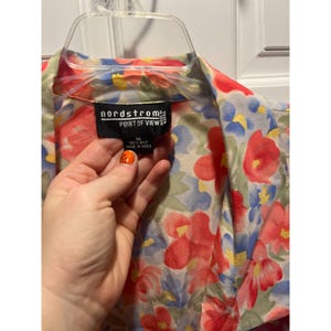 May include: A floral print silk blouse with red, blue, and yellow flowers on a light background. The label reads "nordstrom POINT OF VIEW" and "100% silk MADE IN KOREA".