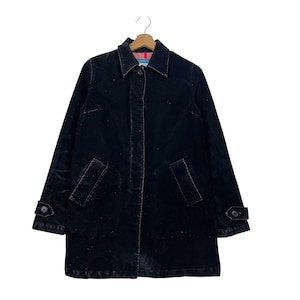 Peut inclure: Un manteau en jean bleu marine foncé doté d'un col classique, d'une patte de boutonnage sur le devant et de deux poches latérales. Les manches présentent des poignets boutonnés réglables et la doublure intérieure est rayée rose et bleu clair.