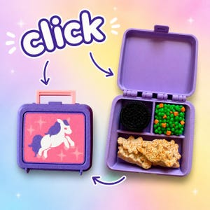 May include: A purple plastic lunchbox with a pink panel featuring a white unicorn graphic. The lunchbox is shown closed and open, revealing three internal compartments containing miniature toy food items: a black cookie, green peas, and a tan sandwich.