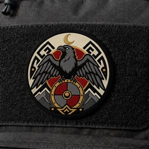 May include: A circular patch featuring a black raven with spread wings perched atop a round shield divided into red and grey segments. The design includes a gold crescent moon, geometric patterns, and mountain silhouettes against a red background.