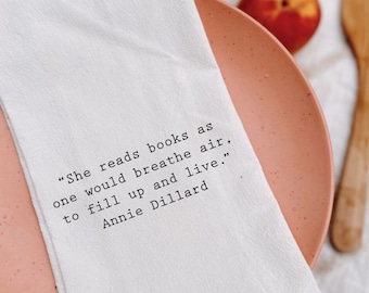 Puede incluir: Toalla de cocina blanca con una cita de Annie Dillard: "Ella lee libros como se respira el aire, para llenarse y vivir."