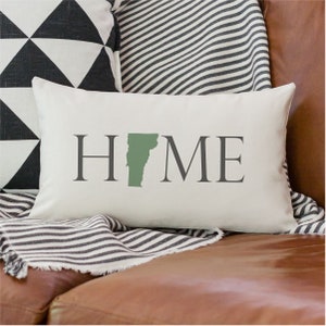May include: White pillow with the word "HOME" in gray text. The letter "O" is replaced with the outline of the state of Vermont in green.