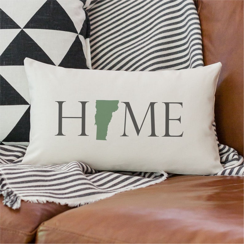 May include: White pillow with the word "HOME" in gray text. The letter "O" is replaced with the outline of the state of Vermont in green.