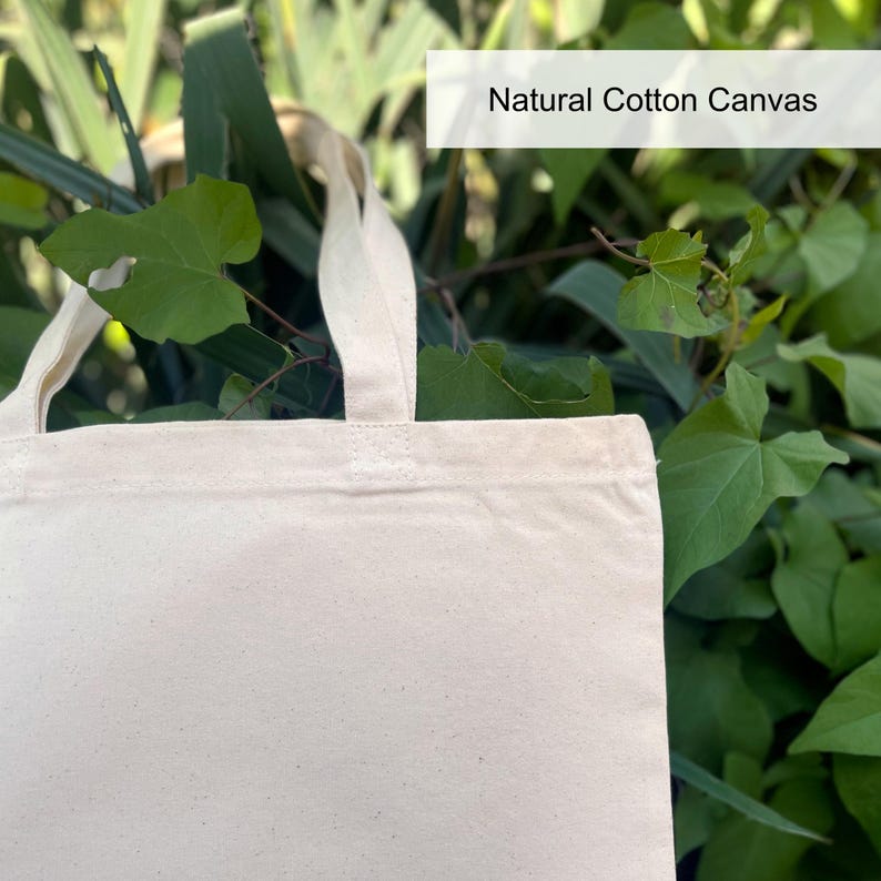May include: A natural cotton canvas tote bag with two handles. The bag is white and has a natural, unbleached look.