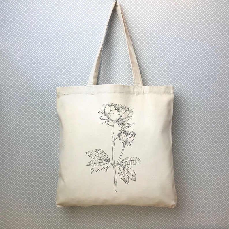 May include: A white canvas tote bag with a black line drawing of a peony flower and the word "Peony" printed on the bag.