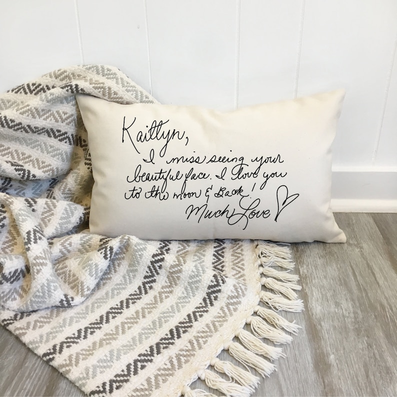 May include: A white pillow with black handwritten text that reads "Kaitlyn, I miss seeing your beautiful face. I love you to the moon & back! Much Love".