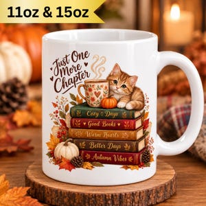 Puede incluir: Una taza de cerámica blanca con un gráfico de un gatito atigrado sobre una pila de cinco libros. El texto dice Just One More Chapter, Cozy Days, Good Books, Warm Hearts, Better Days y Autumn Vibes. El diseño incluye calabazas y hojas.