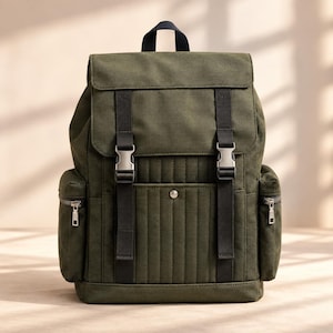 May include: An olive green backpack featuring a top flap with two black vertical straps and silver-toned side-release buckles. The front panel has vertical quilted stitching, a central metal snap button, and two side pockets with silver zippers.