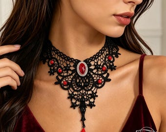 May include: A black lace choker necklace featuring an intricate woven pattern, accented with small round red and black beads. A central oval red gemstone set in a silver-toned frame serves as the focal point, with a dangling red teardrop bead.