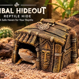 Puede incluir: Un refugio para reptiles de resina marrón con forma de pequeña cabaña y acabado texturizado similar a la madera, con una máscara tallada en la fachada frontal y un dragón barbudo descansando en la entrada. El texto dice TRIBAL HIDEOUT REPTILE HIDE.