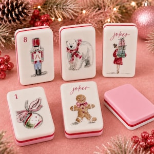 Può includere: Sei tessere da gioco rettangolari con angoli arrotondati, superfici bianche e bordi rosa. I disegni includono uno schiaccianoci, un orso polare con sciarpa rossa, una persona con regali, una pallina di Natale, un omino di pan di zenzero e una tessera vuota.