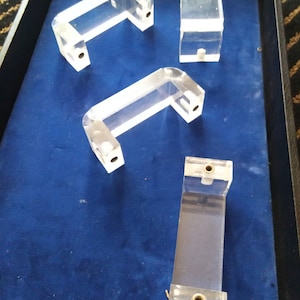 May include: Four clear acrylic display stands with brass screws. The stands are in a blue velvet lined box.