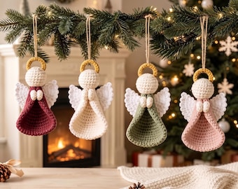 May include: Four handmade crochet angel ornaments hanging from a pine branch. Each angel features a round cream head, a yellow halo, white wings, and a cone-shaped dress in deep red, cream, sage green, or soft pink, suspended by a simple twine loop.