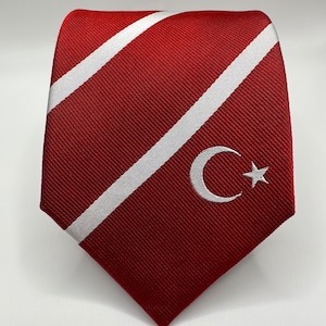 Op de afbeelding: Een rode zijden stropdas met witte diagonale strepen en een witte geborduurde halve maan en ster.