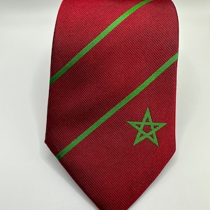 Op de afbeelding: Een rode stropdas met groene diagonale strepen en een groene vijfpuntige ster in het midden.