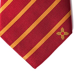 May include: Red and yellow striped tie with a small embroidered symbol of the state of New Mexico.
