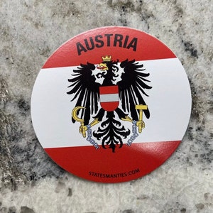 Puede incluir: Una pegatina redonda con la bandera de Austria. La bandera es roja, blanca y roja con un águila negra en el centro. El águila tiene una corona dorada y sostiene una hoz y un martillo en sus garras. La pegatina dice "AUSTRIA" en la parte superior y "STATESMANTIES.COM" en la parte inferior.