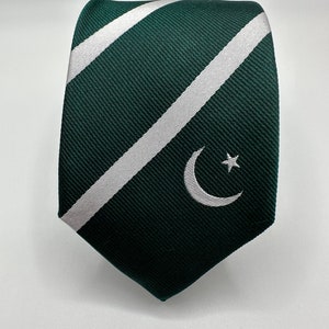 Op de afbeelding: Een groene en witte gestreepte stropdas met een wit halve maan en ster ontwerp.