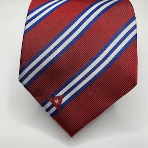 Op de afbeelding: Een rood-wit gestreepte stropdas met een klein geborduurd Cubaans vlaggetje in de rechterbenedenhoek.