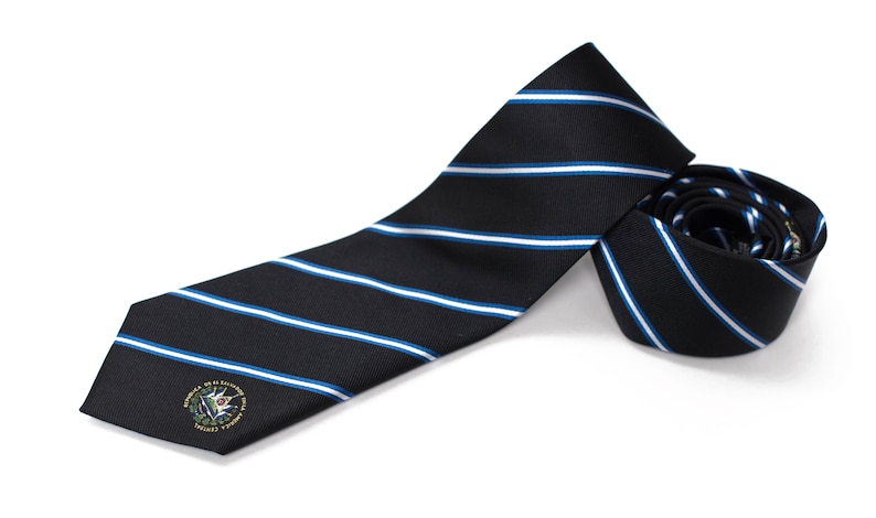 Op de afbeelding: Een zwart-blauwe gestreepte stropdas met een klein geborduurd embleem met een groene plant en de tekst "Seal of the United States Military Academy".