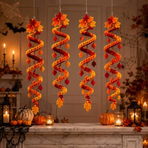 May include: Four hanging spiral decorations made of crocheted yarn in shades of orange, yellow, and red. Each spiral features a large crocheted maple leaf at the top and smaller leaves attached along the length of the twisted, dangling structure.