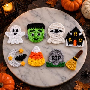 May include: A collection of eight crocheted Halloween-themed appliques including a white ghost, a green Frankenstein monster, a white mummy, a black haunted house, a gray crescent moon with stars and a bat, a candy corn, a gray tombstone with RIP, and a broom.