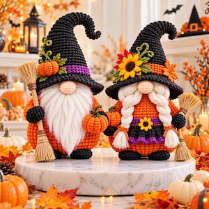 Peut inclure: Deux figurines de gnomes au crochet déguisées en sorcières. Le gnome de gauche a une longue barbe blanche, un chapeau noir avec une petite citrouille orange et tient un balai. Celui de droite a des tresses blanches et un chapeau à tournesol.